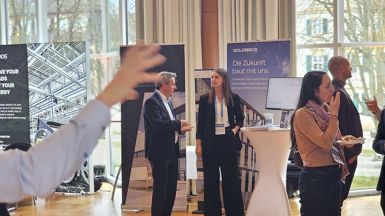 Zwei Teilnehmer im Austausch am Stand von GOLDBECK auf dem Fachkongress Fabrikplanung 2025 in Ludwigsburg