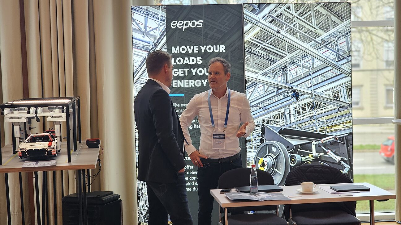 Zwei Teilnehmer im Austausch am Stand von eepos auf dem Fachkongress Fabrikplanung 2025 in Ludwigsburg