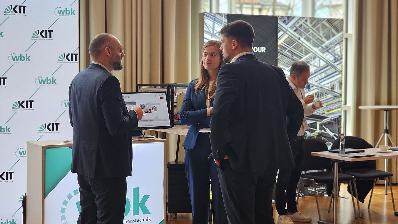 Teilnehmer im Austausch am Stand von wbk im Ausstellerbereich des Deutschen Fachkongress Fabrikplanung 2025