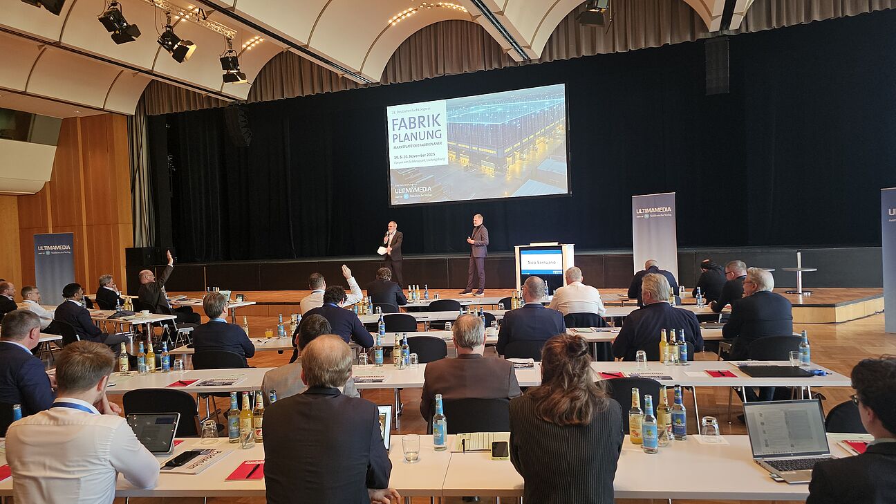 Nico Santuario mit Dr. Jürgen Bischoff auf der Bühne. Die Teilnehmer stellen Fragen zum Vortrag. Fachkongress Fabrikplanung 2025