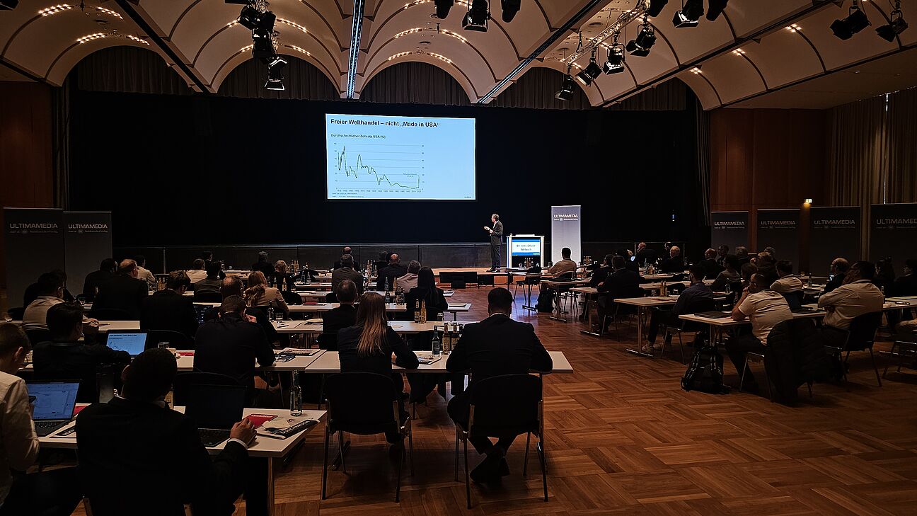 Konferenzraum mit Teilnehmern im Vordergrund während des Vortrags von Dr. Jens-Oliver Niklasch beim Fachkongress Fabrikplanung 2025 in Ludwigsburg