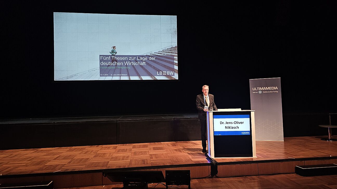Dr. Jens-Oliver Niklasch auf der Bühne während seines Vortrags auf dem Deutschen Fachkongress Fabrikplanung 2025 in Ludwigsburg.  